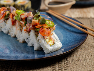 Avocado Crab Sushi Roll with Salmon and Jalapeño Garnish on Blue Ceramic Plate