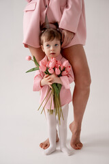 mom and daughter with tulip flowers on a white isolated background, a place and space for text, mom and child in pink clothes, mother's day