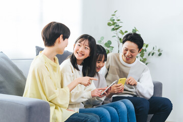 笑顔でスマホを見る小学生の女の子の家族