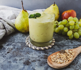 glass with avocado smoothie and fruits around and rustic background