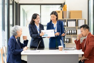Group of Asian business people working in office on charts and graphs showing results of successful teamwork. Happy team meeting. Business data charts. Conference room.