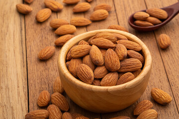 Dry roasted Almonds in wooden bowl on wooden table.Heap of almond.