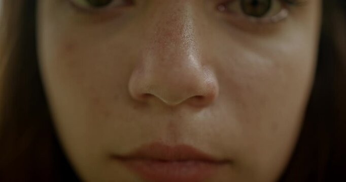 Close-up of a young woman's face, her eyes looking directly at the camera. The video emphasizes her natural beauty and subtle emotions.