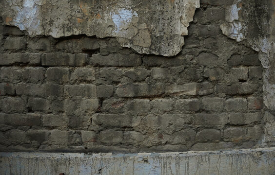 Old damaged wall background with peeling stucco and exposed dark brickwork texture