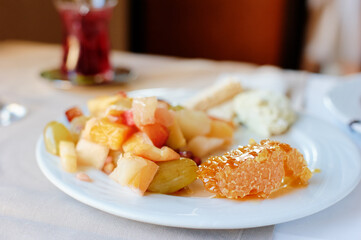 Fresh Fruit Salad with Honeycomb and Cheese on a White Plate..