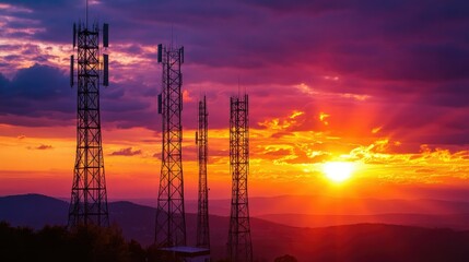 Fiery sunset light glows behind massive telecom towers, emphasizing the striking contrast between technology and natural beauty