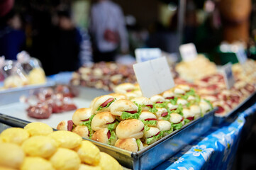 A close-up of a market stall displaying a variety of freshly baked bread rolls and pastries.