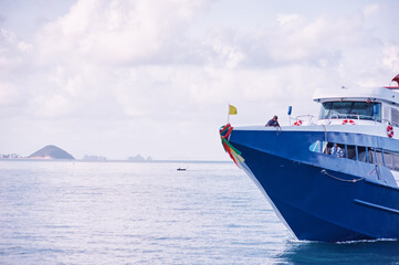 Blue Passenger Ferry Navigating Calm Waters Near Distant Islands.