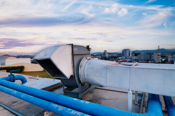 Rooftop Ventilation System with Urban Cityscape in the Background During Sunset..