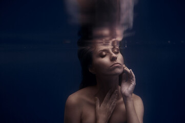 Underwater portrait showcasing woman immersed in tranquil surroundings, capturing ethereal beauty and calm emotions. The image evokes a sense of mystery and a connection to peaceful underwater worlds.