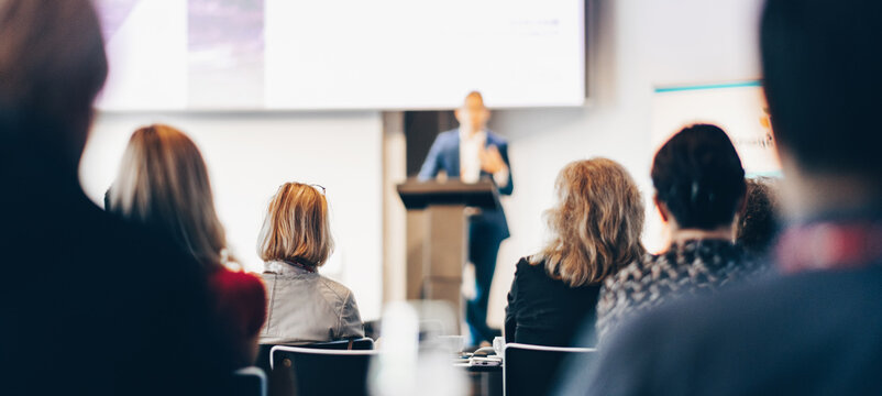 Speaker giving a talk in conference hall at business event. Rear view of unrecognizable people in audience at the conference hall. Business and entrepreneurship concept
