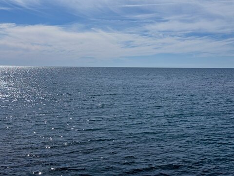 Shiny blue sea and sky with soft clouds