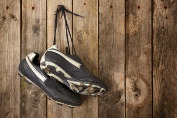Black soccer shoes hanging from laces on wooden wall