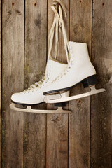 Old ice skates hanging from laces on wooden wall