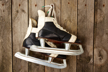 Ice hockey skates hanging from laces on a wooden wall