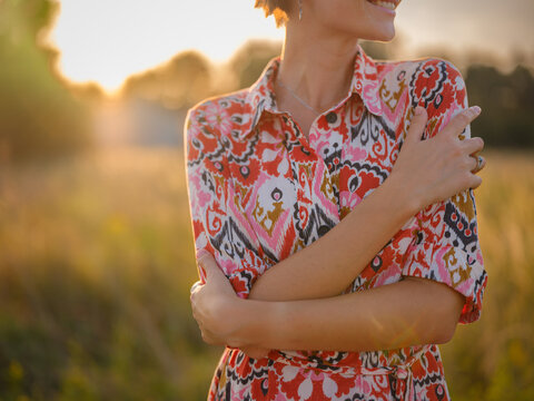 young woman embracing herself, self-love in action, mental health advocate, practicing self-care for finding inner peace, in European countryside