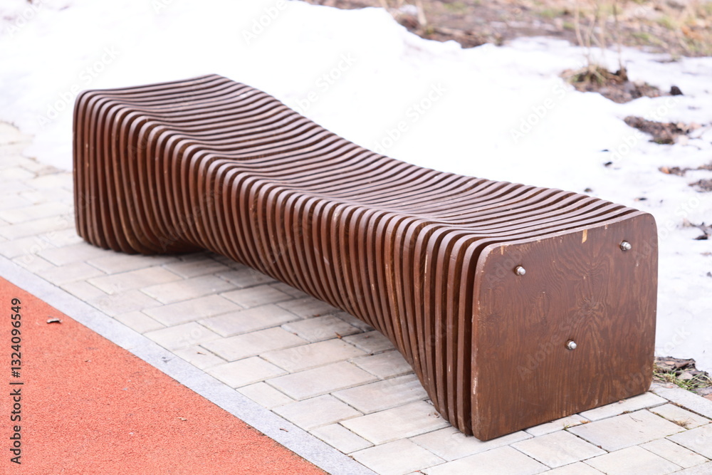 Poster a simple wooden bench placed on the edge of a sidewalk, suitable for urban scenes or public spaces.
