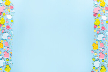 Easter sweets and candies background. High-colored blue flat lay with various Easter chocolate eggs, treats, symbols of easter sheep, bunny, carrot, flowers, cookies, top view copy space, frame
