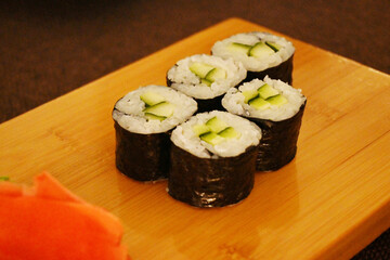Exquisite sushi rolls with avocado, pickled ginger in the foreground on a stylish board, Japanese cuisine.