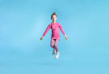 Obraz premium Cute little girl with jump rope on light blue background