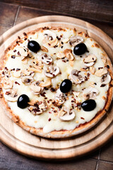 Pizza with champignons, black olives and mozzarella cheese. Wooden background. Soft focus.
