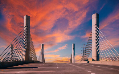 Fototapeta premium Modern cable bridge on highway at sunset, a dramatic cloudscape over the deserted road