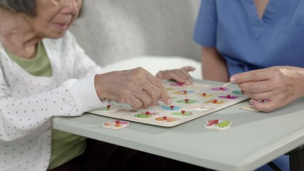 Nurse in nursing home helping a senior woman with number puzzle game. Dementia, Alzheimer's disease