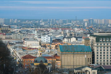 A panoramic view of the Podil district in Kyiv, featuring historic architecture, modern buildings, and the Ferris wheel on Kontraktova Square.