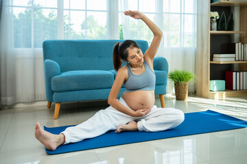 Pregnant Asian woman practicing prenatal stretching exercise for flexibility and relaxation at home