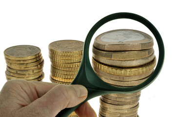 Examiner des pièces de monnaie en euro à la loupe en gros plan sur fond blanc.