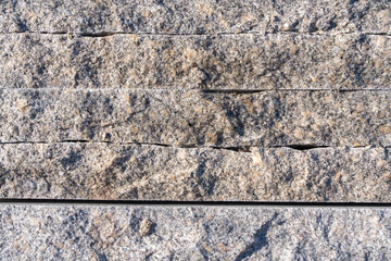 gray granite stones 6-8 cm thick superimposed one on another in bright sunlight 