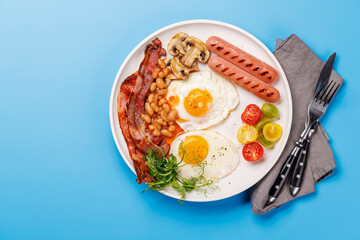 A classic breakfast plate featuring sunny-side-up eggs, crispy bacon, sausages, and fresh tomatoes