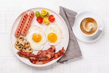 A classic breakfast plate featuring sunny-side-up eggs, crispy bacon, sausages, and fresh tomatoes