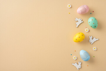 Vibrant colored Easter eggs and intricate rabbit decorations spread on a beige surface surrounded...