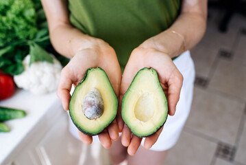 Woman holding a halved avocado in her hands
