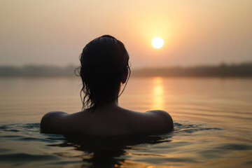 Fototapeta premium Woman immersing herself in the Ganges River during a beautiful sunset, enjoying a moment of peace and tranquility