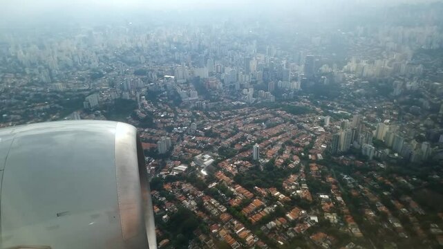 View through the airplane window during a flight over the city of S&atilde;o Paulo, passing over the Vila Madalena and Pinheiros region on the way to Congonhas airport.