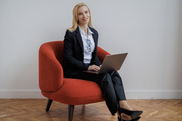 Happy woman with her laptop on a red couch.