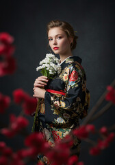 A white woman wearing a kimono holding a bouquet of flowers- traditional attire