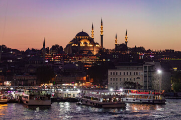 Obraz premium Istanbul, Turkiye - November 7, 2023: skyline from Galata bridge over Golden Horn by night, with Suleymaniye mosque and fish boat restaurants in Eminonu