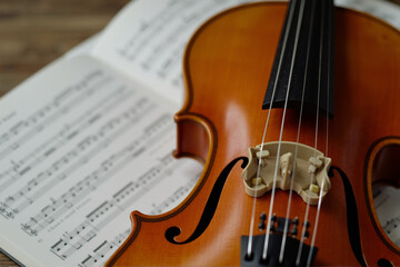 Fototapeta premium Close-up of a violin resting on top of an open sheet of music.