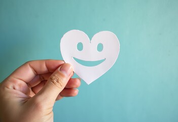 Positive Vibes: Hand Holding a Paper Cut Smile Face Represents Mental Health Awareness, Assessment, and Support for World Mental Health Day Initiatives Globally.

