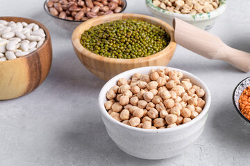 Dry chickpeas and mung beans in a bowls on gray table background. Mixed pulses for healthy and balanced diet, plant-based protein sources