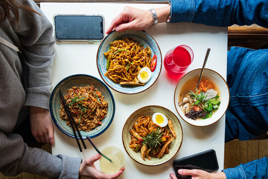Friends savor flavorful noodles and dishes while sharing drinks at the table