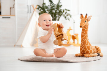 a kid is playing with wooden toys at home in the children's room, a small child boy is smiling playing with a typewriter in the room against the background of a wigwam © Any Grant