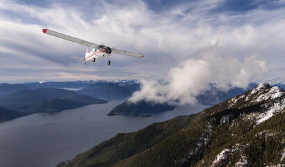 Small Airplane Flying Over Mountain Range Under Blue Skies and White Clouds