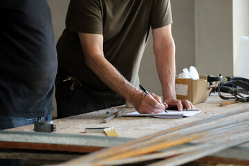 Construction workers taking notes on papers while projecting construction details