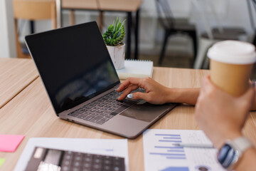 Close up Business Female using calculator and laptop for do math finance on wooden desk, tax, accounting, statistics and analytical research concept	
