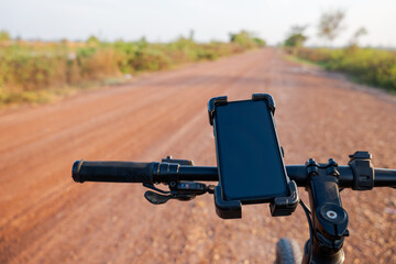 Smartphone in the holder attached to the handlebar of a mountain bike while riding on the off-road trail in the field
