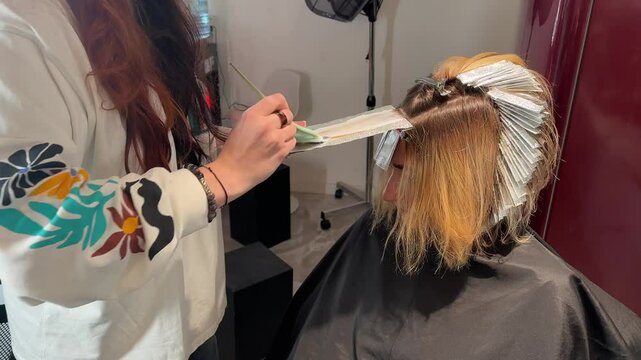  gives a haircut to a client with wet blonde hair in a salon. A close-up of hands, scissors, and a comb shows the precision of the work